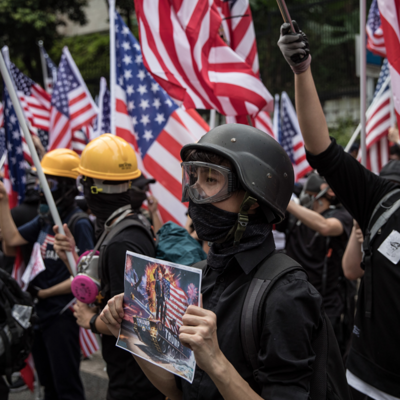 Image of protestors wearing protective gear and holding American flags